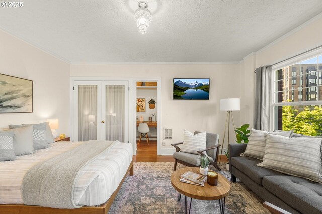 bedroom with french doors, a textured ceiling, crown molding, wood finished floors, and baseboards
