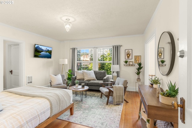 bedroom featuring ornamental molding, wood finished floors, a textured ceiling, and baseboards