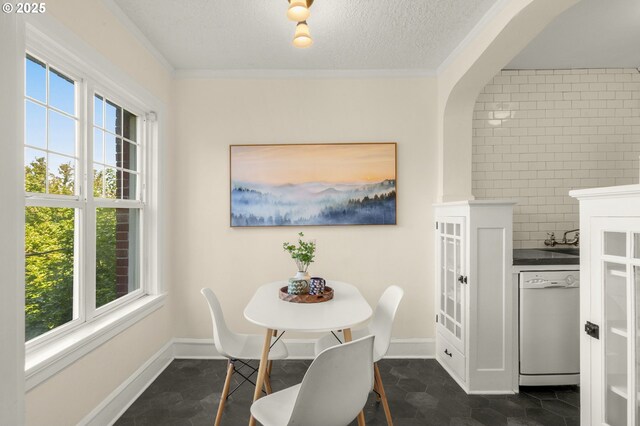dining area with a textured ceiling, crown molding, and baseboards