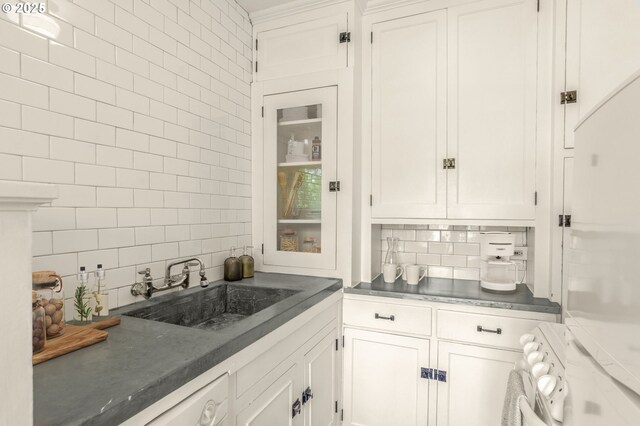 kitchen with decorative backsplash, a sink, white cabinets, and white appliances