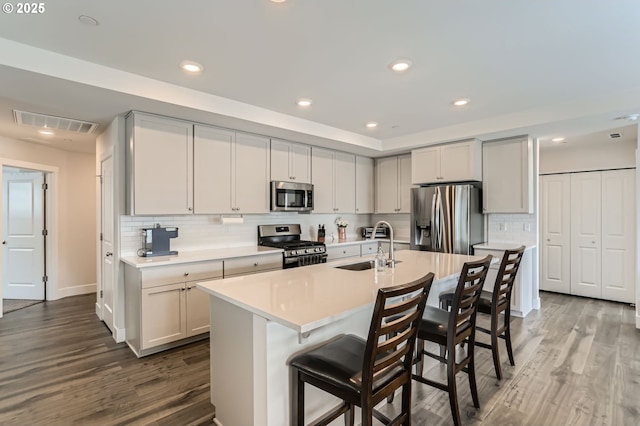 kitchen with light countertops, visible vents, appliances with stainless steel finishes, a sink, and wood finished floors