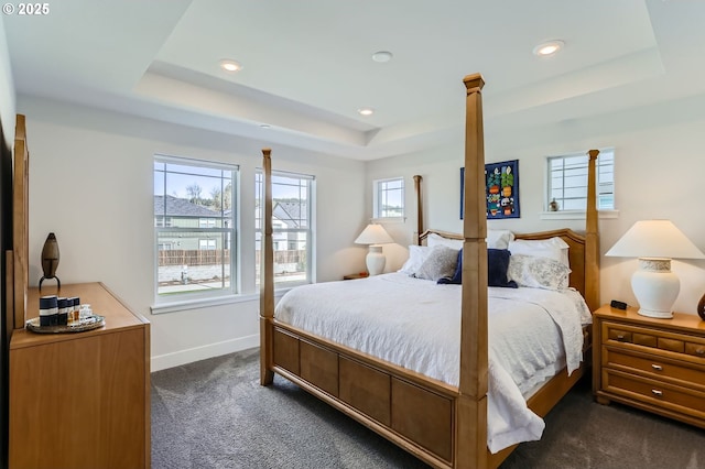 bedroom featuring dark colored carpet, a raised ceiling, and baseboards