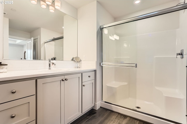 bathroom with recessed lighting, wood finished floors, vanity, decorative backsplash, and a stall shower