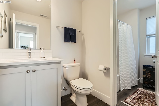 bathroom with visible vents, toilet, vanity, wood finished floors, and baseboards