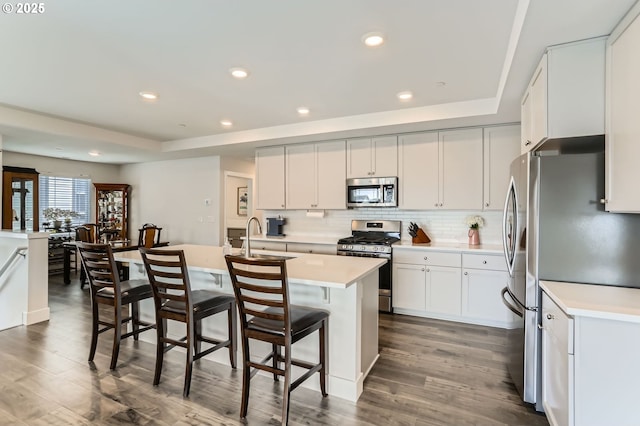 kitchen featuring a breakfast bar, appliances with stainless steel finishes, a raised ceiling, and light countertops