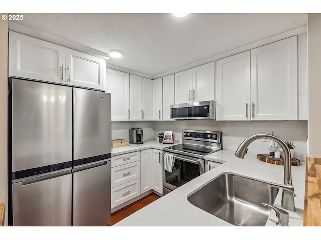 kitchen with a sink, white cabinetry, appliances with stainless steel finishes, and light countertops