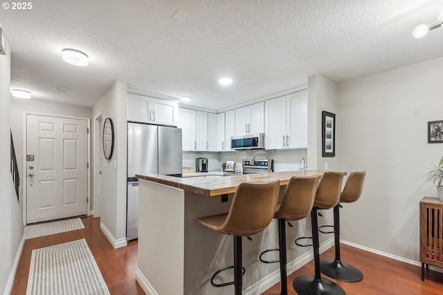 4880 SW Scholls Ferry Rd Unit 14, Portland, OR 97225 - kitchen with stainless steel appliances, a textured ceiling, dark wood-type flooring, and a peninsula