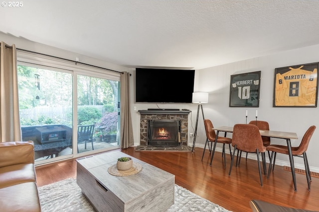 4880 SW Scholls Ferry Rd Unit 14, Portland, OR 97225 - living room featuring visible vents, wood finished floors, a stone fireplace, baseboards, and a textured ceiling