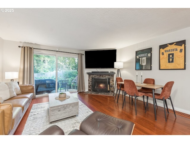 living area featuring baseboards, wood finished floors, and a fireplace