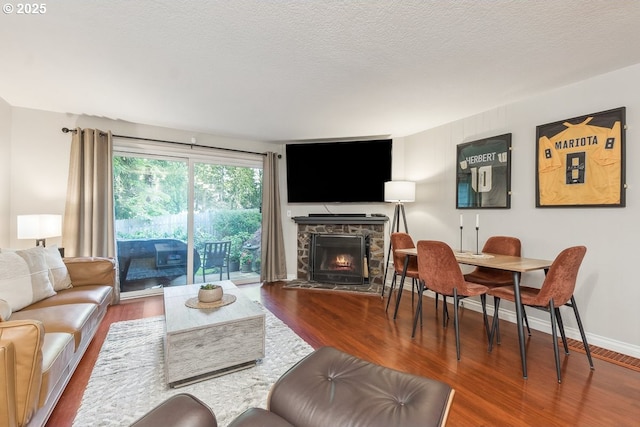 4880 SW Scholls Ferry Rd Unit 14, Portland, OR 97225 - living room with a stone fireplace, baseboards, a textured ceiling, and wood finished floors