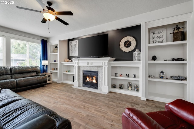 12241 Mimosa Way, Oregon City, OR 97045 - living room featuring ceiling fan, a textured ceiling, built in shelves, wood finished floors, and a fireplace with flush hearth