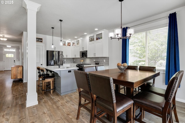 12241 Mimosa Way, Oregon City, OR 97045 - dining area with light wood-style floors, ornate columns, and a chandelier