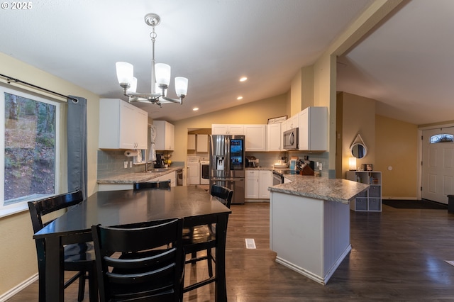 kitchen with hanging light fixtures, stainless steel appliances, a notable chandelier, decorative backsplash, and white cabinetry