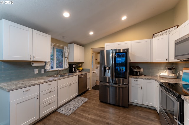 kitchen with sink, appliances with stainless steel finishes, white cabinetry, vaulted ceiling, and dark wood-type flooring