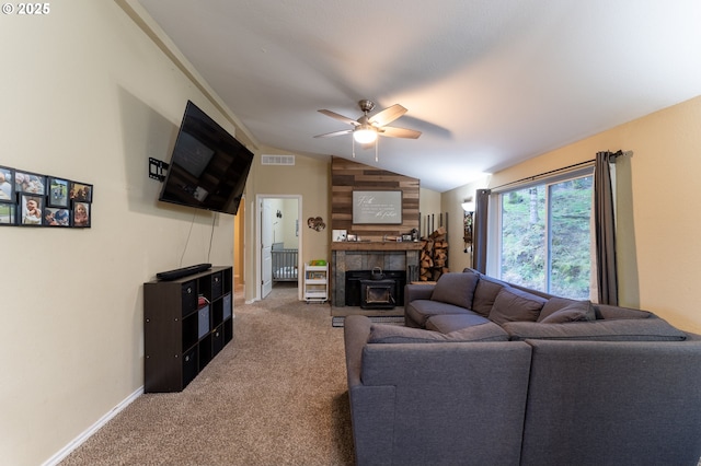 living room with vaulted ceiling, carpet flooring, ceiling fan, and a wood stove