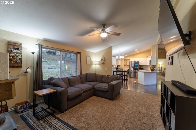 carpeted living room with lofted ceiling and ceiling fan with notable chandelier