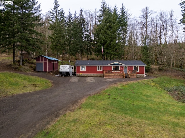 view of front of property with a deck, a front lawn, and a shed