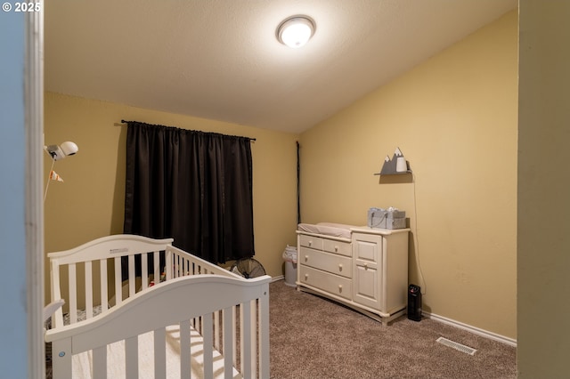 bedroom with lofted ceiling, a crib, and carpet