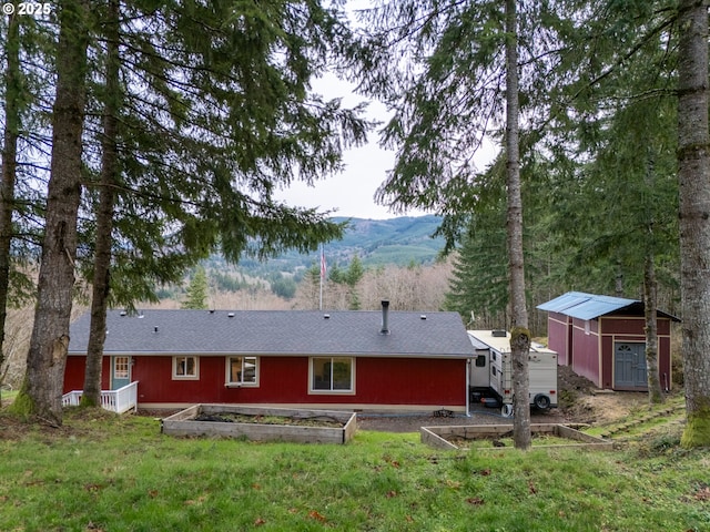 back of house with a lawn, a storage unit, and a mountain view