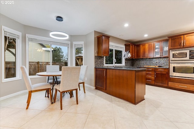 kitchen featuring tasteful backsplash, glass insert cabinets, baseboards, appliances with stainless steel finishes, and a peninsula