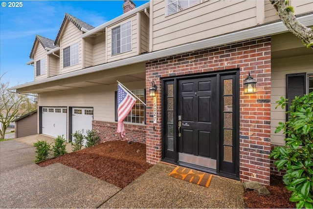 property entrance with a garage, brick siding, and driveway