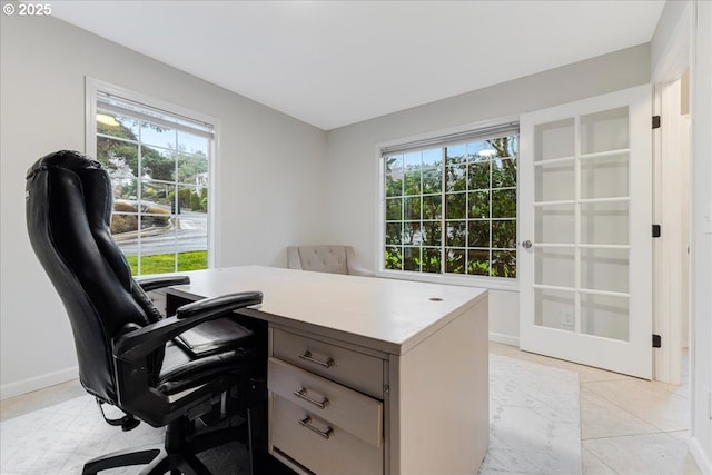 office with light tile patterned floors, a healthy amount of sunlight, and baseboards