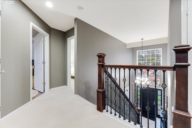 hallway with baseboards, an upstairs landing, and carpet