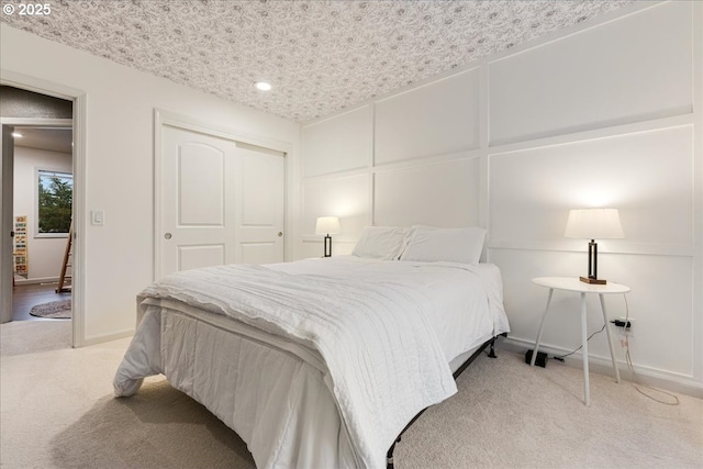 bedroom with a decorative wall, carpet flooring, baseboards, and a closet