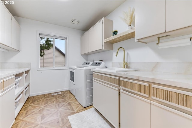 laundry area featuring washer and dryer, baseboards, cabinet space, and a sink