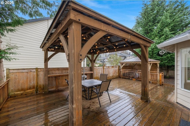 wooden deck with a gazebo, outdoor dining area, and fence