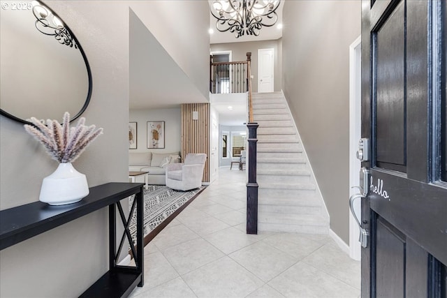 entryway featuring baseboards, a chandelier, stairs, light tile patterned floors, and a towering ceiling