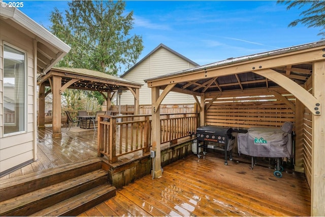 wooden terrace with a gazebo, fence, and a grill