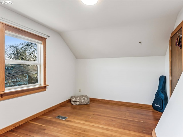 additional living space with hardwood / wood-style flooring and vaulted ceiling