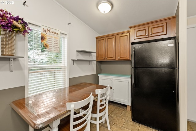 kitchen with brown cabinets, lofted ceiling, light countertops, freestanding refrigerator, and white cabinets