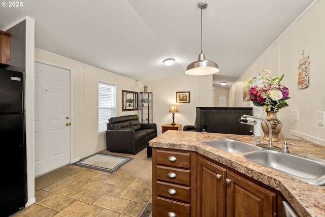 kitchen with decorative light fixtures, freestanding refrigerator, vaulted ceiling, light countertops, and a sink