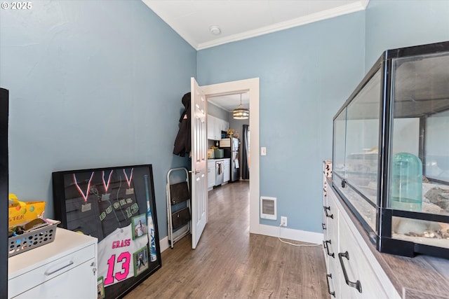 interior space with crown molding, baseboards, visible vents, and wood finished floors