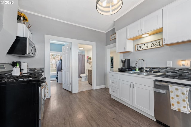 kitchen featuring crown molding, a sink, decorative backsplash, and stainless steel appliances