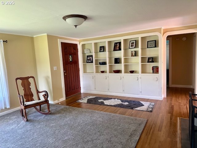 foyer with arched walkways, baseboards, and wood finished floors