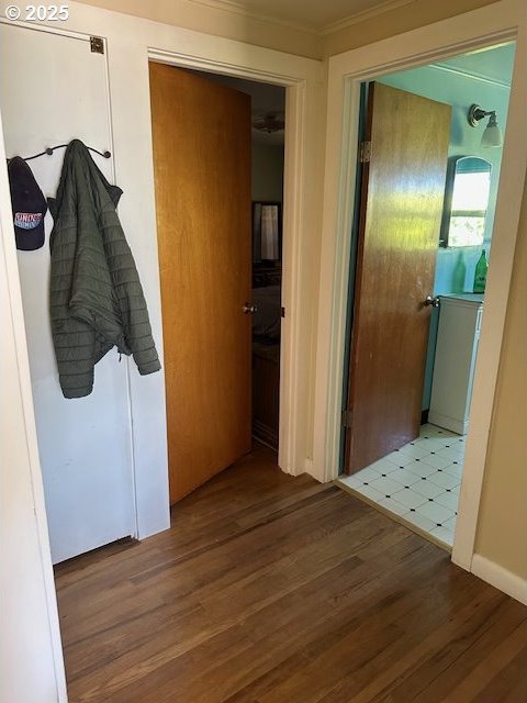 corridor featuring washer / dryer, crown molding, and wood finished floors