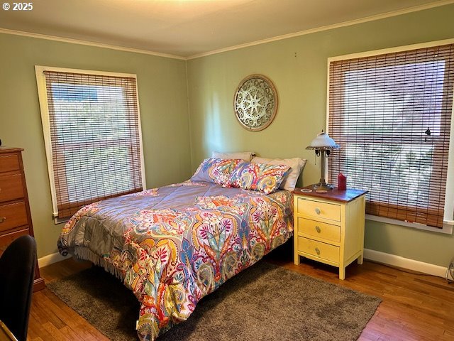 bedroom with crown molding, baseboards, and wood finished floors