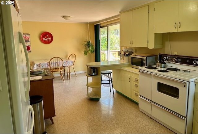 kitchen with baseboards, light countertops, and white appliances