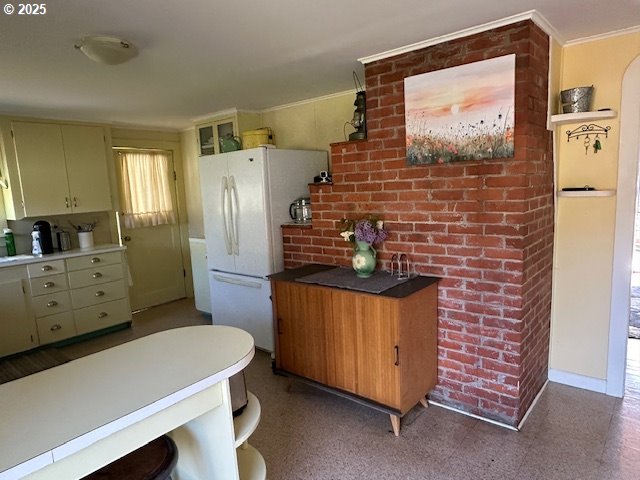 kitchen featuring crown molding, freestanding refrigerator, and open shelves