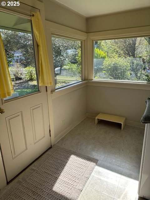 unfurnished sunroom with baseboards and carpet