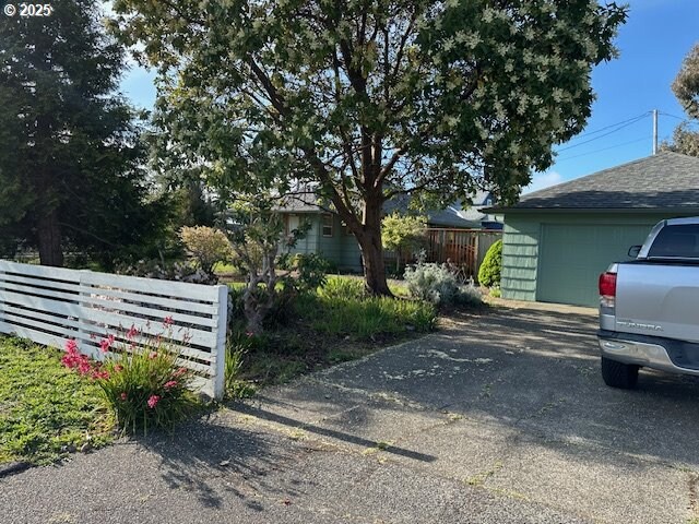 exterior space with fence, an outbuilding, aphalt driveway, and a garage
