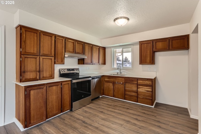 kitchen with a textured ceiling, sink, stainless steel appliances, and dark wood-type flooring