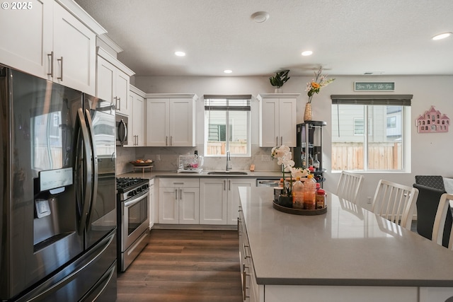 825 S 23rd Ave, Cornelius, OR 97113 - kitchen with stainless steel appliances, a sink, dark wood-type flooring, a kitchen island, and backsplash