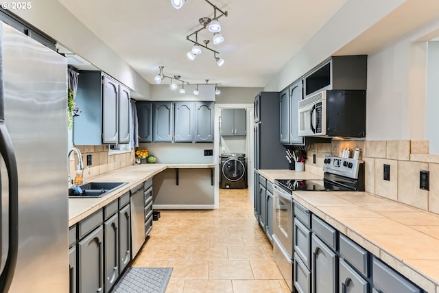 kitchen featuring backsplash, washer / clothes dryer, sink, and stainless steel appliances