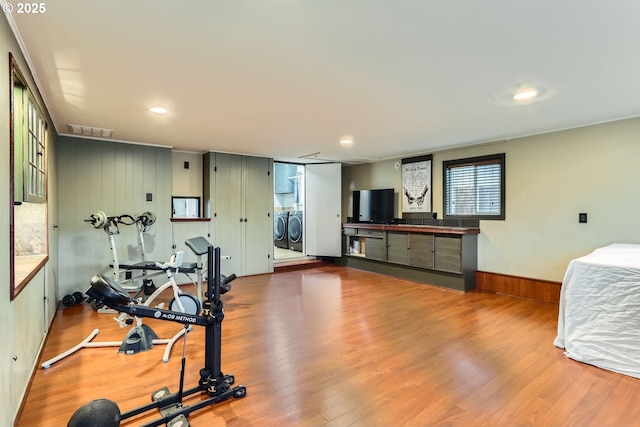 workout area featuring independent washer and dryer, hardwood / wood-style flooring, and wood walls