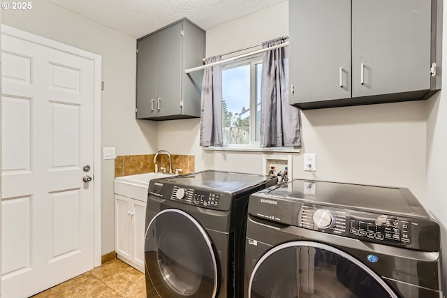 clothes washing area with sink, cabinets, a textured ceiling, washer and clothes dryer, and light tile patterned flooring