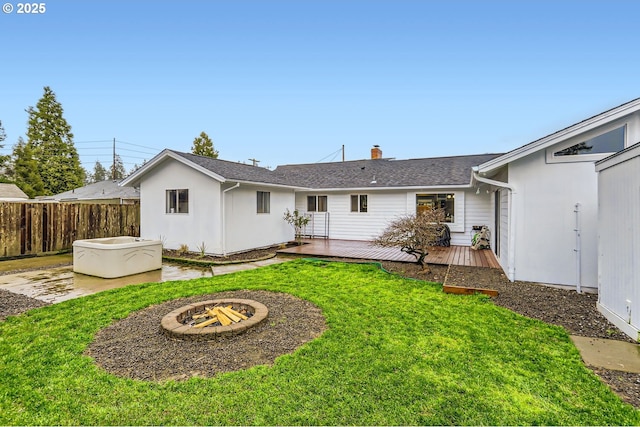 rear view of property featuring a deck, an outdoor fire pit, and a lawn